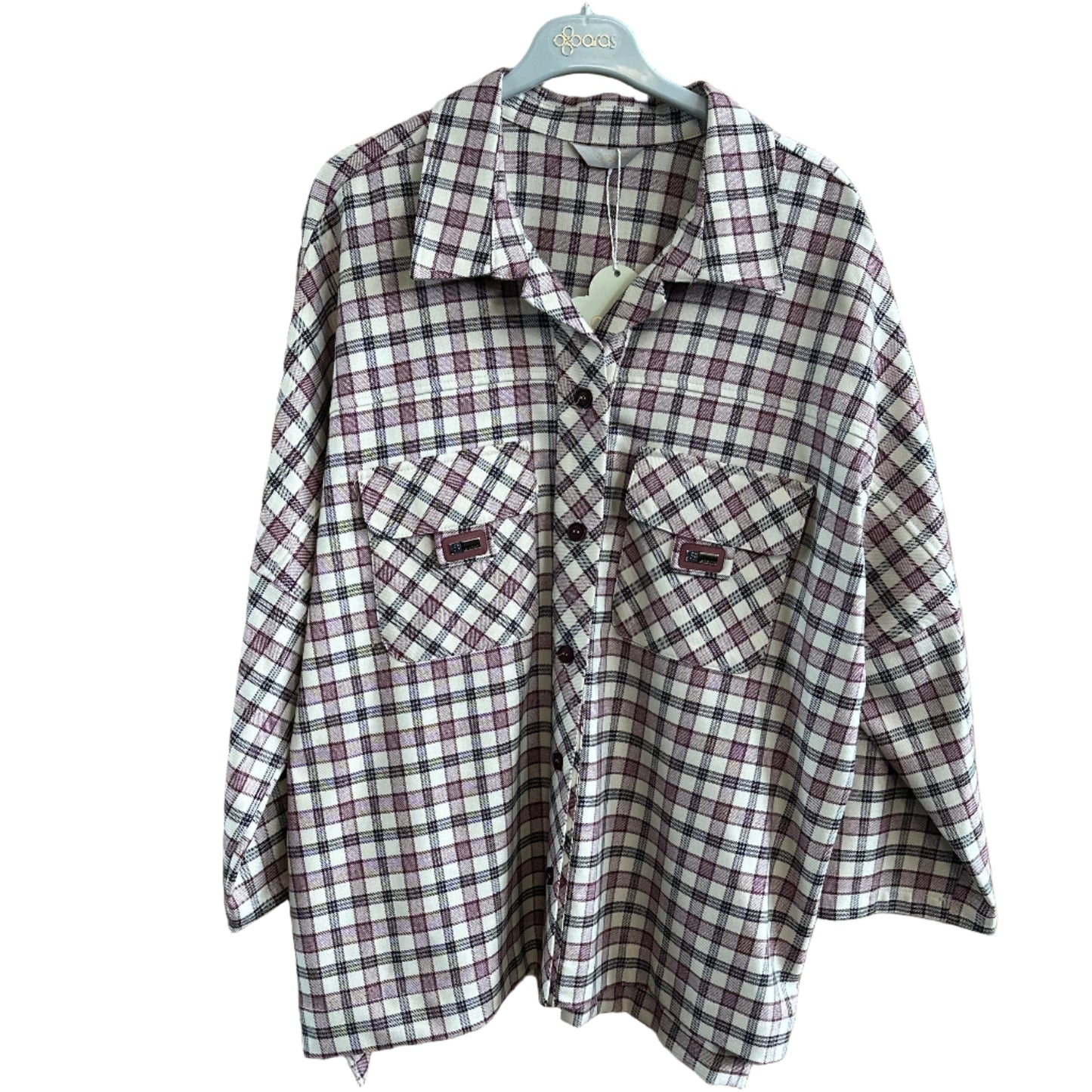 Folded plaid shirt on a wooden surface with a hanger.