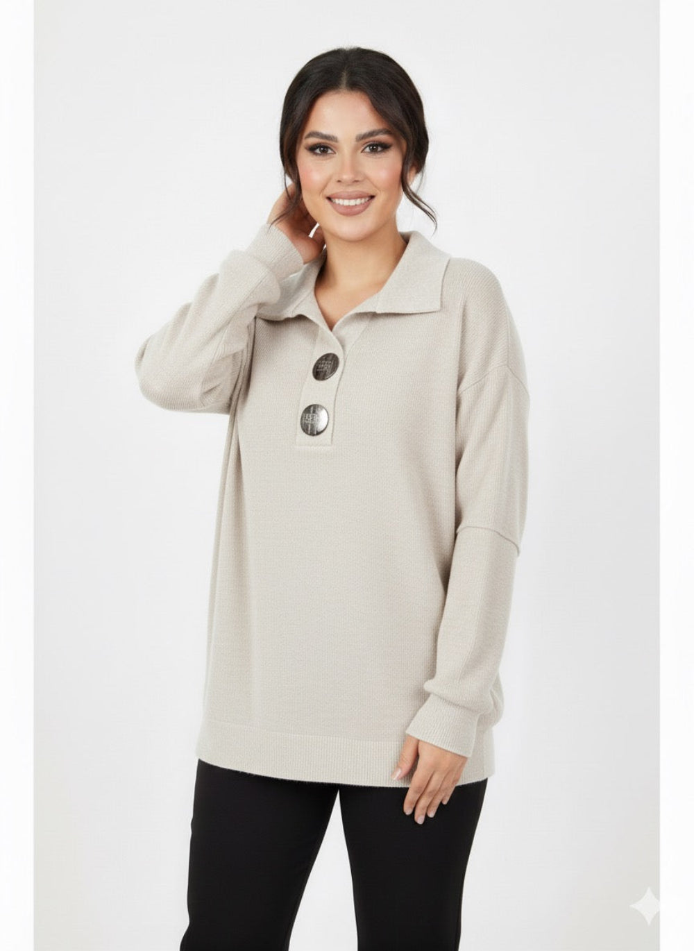 Modelis dėvi šviesiai smėlio („beige“) veliūrinę palaidinę su trimis dekoratyvinėmis sagomis, laisvo kirpimo siluetas.