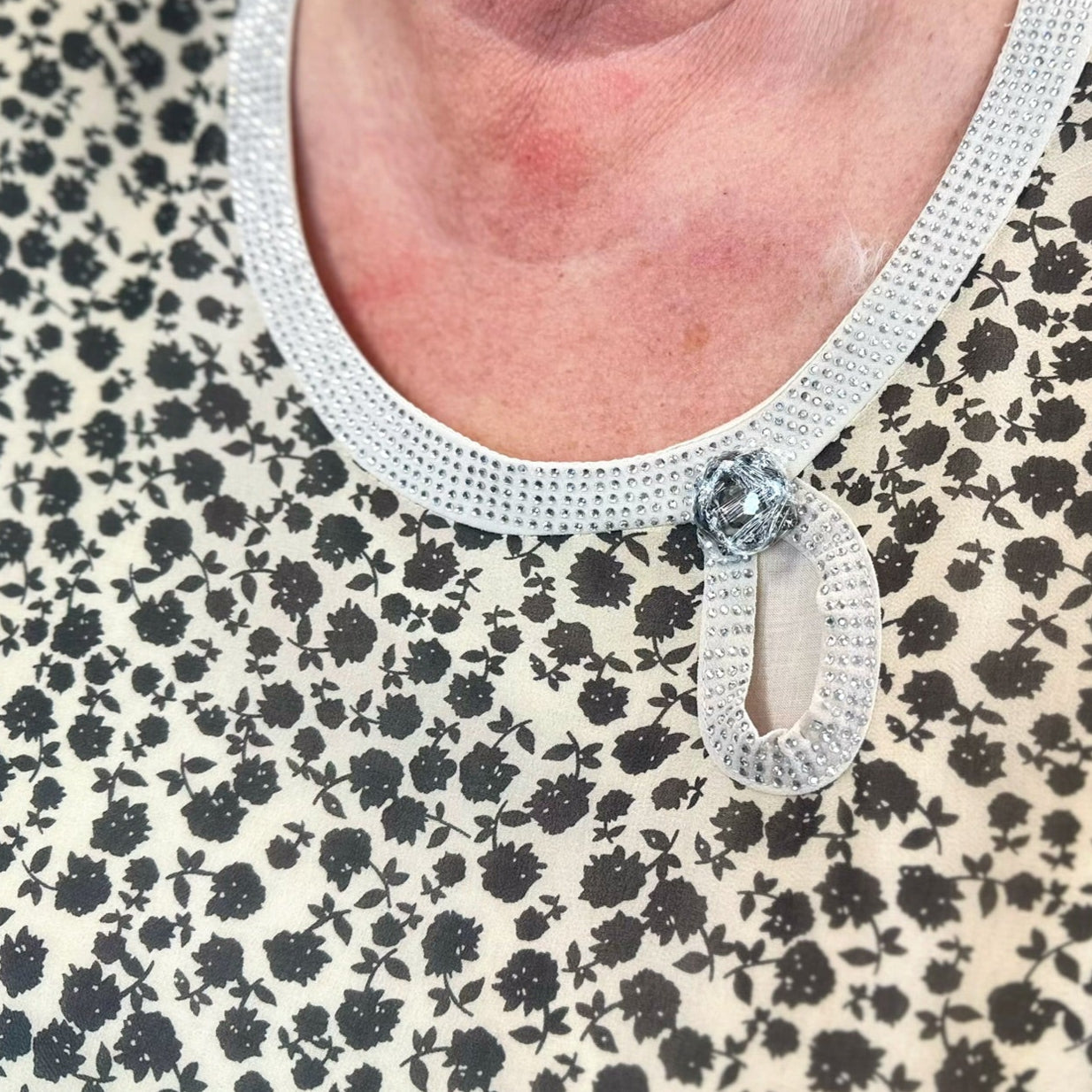 Žėrinti apykaklė ir 3/4 rankovės suteikia šiai suknelei unikalumo ir elegancijos.