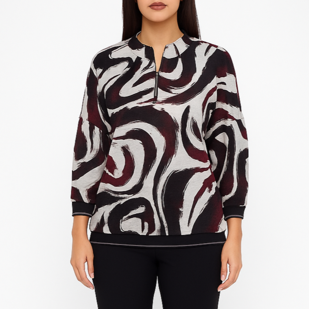 Modelis dėvi juoda–baltą šiltą palaidinę su grafiniu raštu, trumpu užtrauktuku ir 3/4 rankovėmis, dydis 50