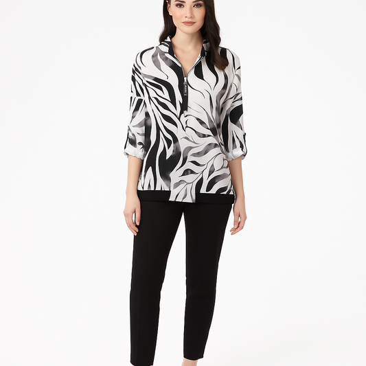 Woman wearing a black and white patterned blouse with black pants on a white background