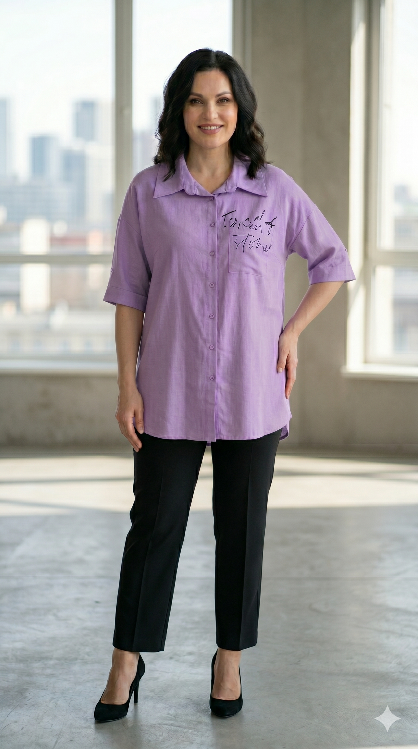 Woman wearing a purple shirt with text in a room with large windows