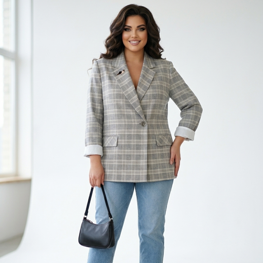 Woman wearing a plaid blazer and jeans with a black handbag indoors.