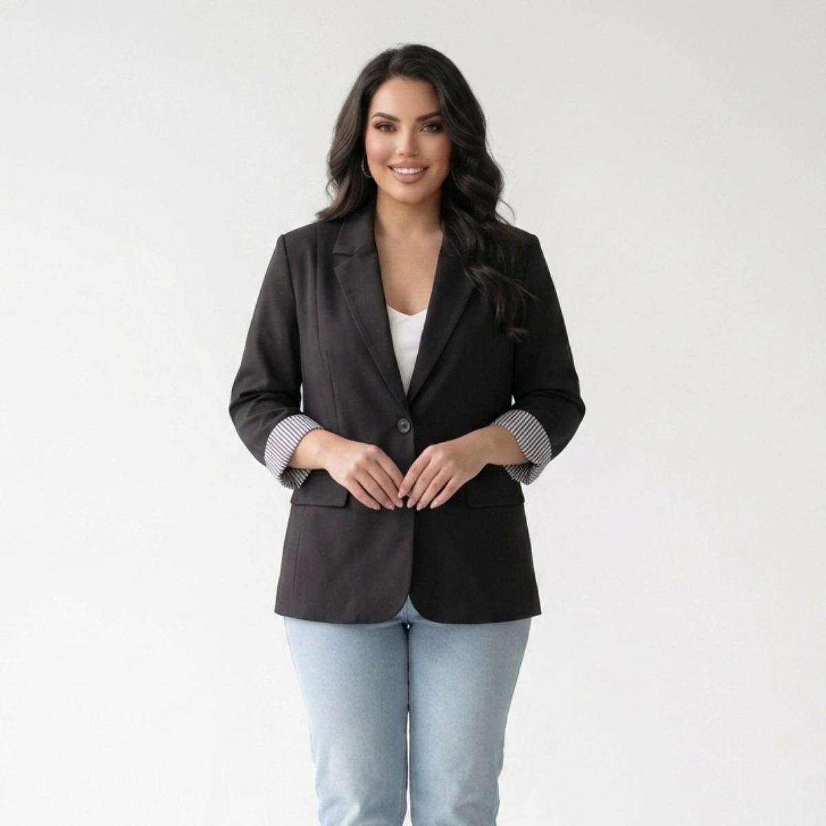 Woman wearing a black blazer and light blue jeans on a white background