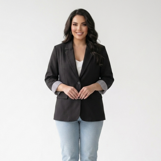 Woman wearing a black blazer and light blue jeans on a white background
