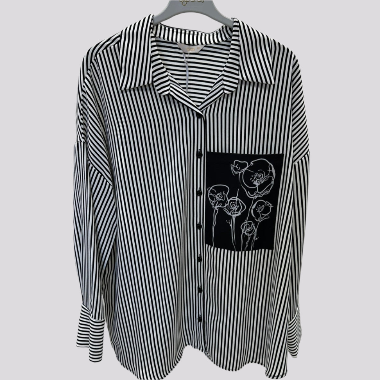 Dryžuoti moteriški marškiniai ant pakabos.