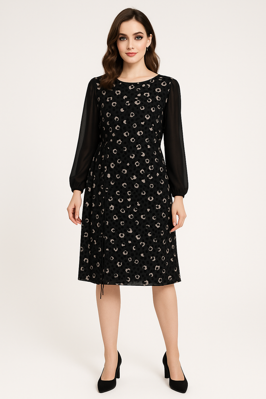 Modelis dėvi juodą suknelę su ilgomis permatomomis rankovėmis ir subtiliu paraukimu ties liemeniu, dydis 46, vaizdas iš priekio