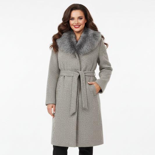 Moteris dėvi pilką paltą su kailine apykakle ir diržu, elegantiškas rudens–žiemos modelis