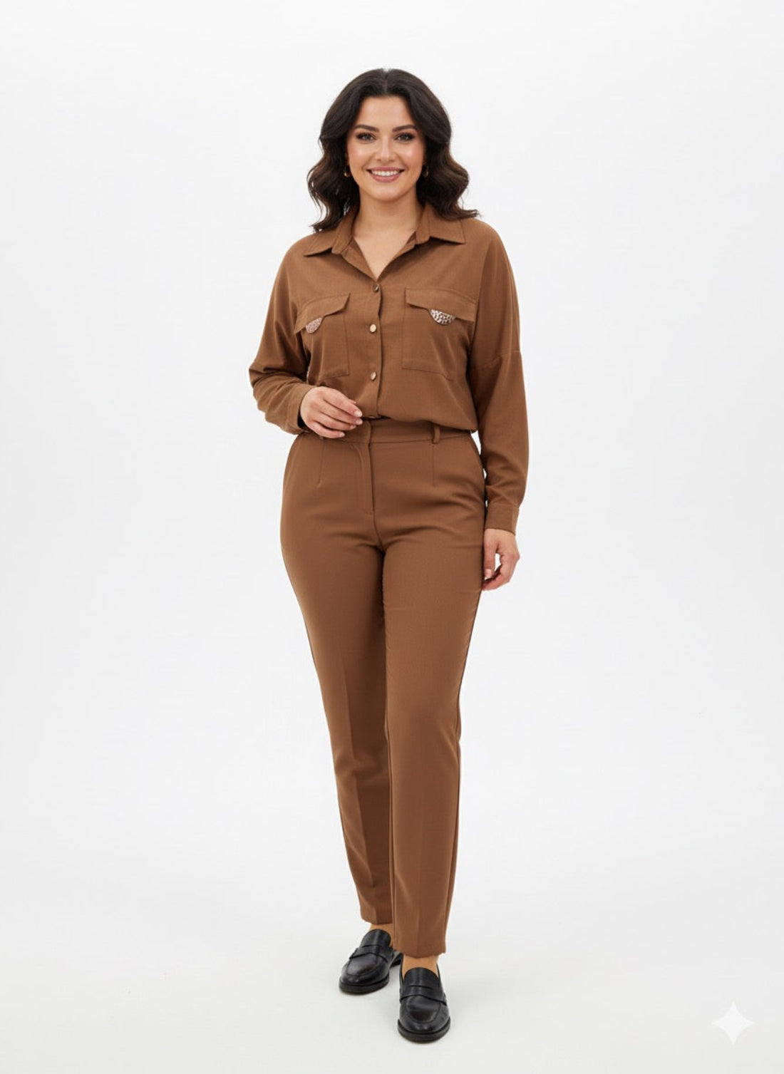 Modelis dėvi rudus moteriškus marškinius su metalinėmis detalėmis ant kišenių ir sagų užsegimu.