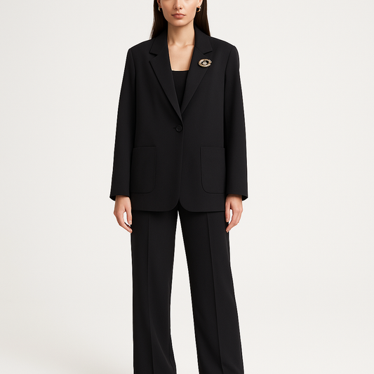 Juodas 2 dalių moteriškas kostiumas – švarkas su nusiimama auksine sege ir kelnės su guma bei kišenėmis, demonstruojamas ant modelio