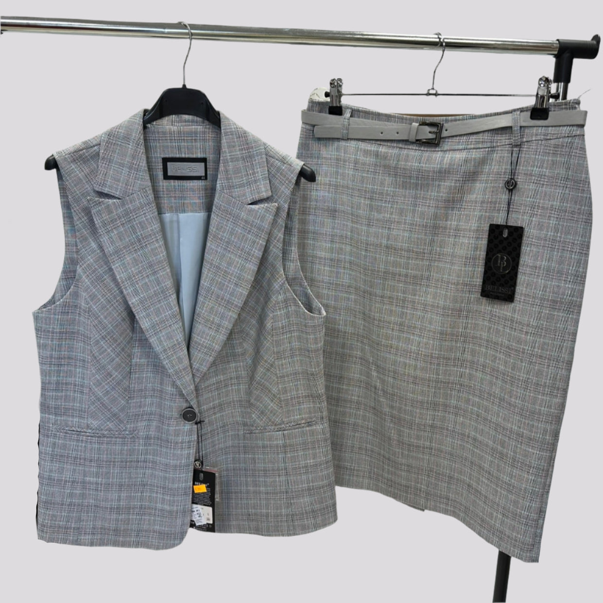 Languotas pilkas moteriškas kostiumėlis su liemene ir sijonu.