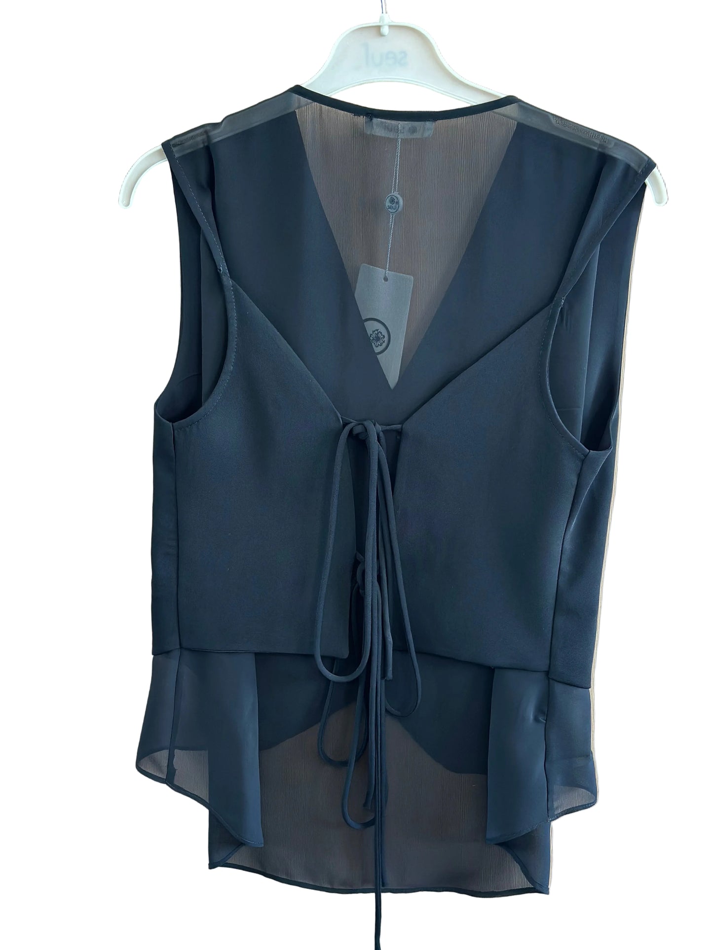 Black sheer top on a white hanger against a beige background