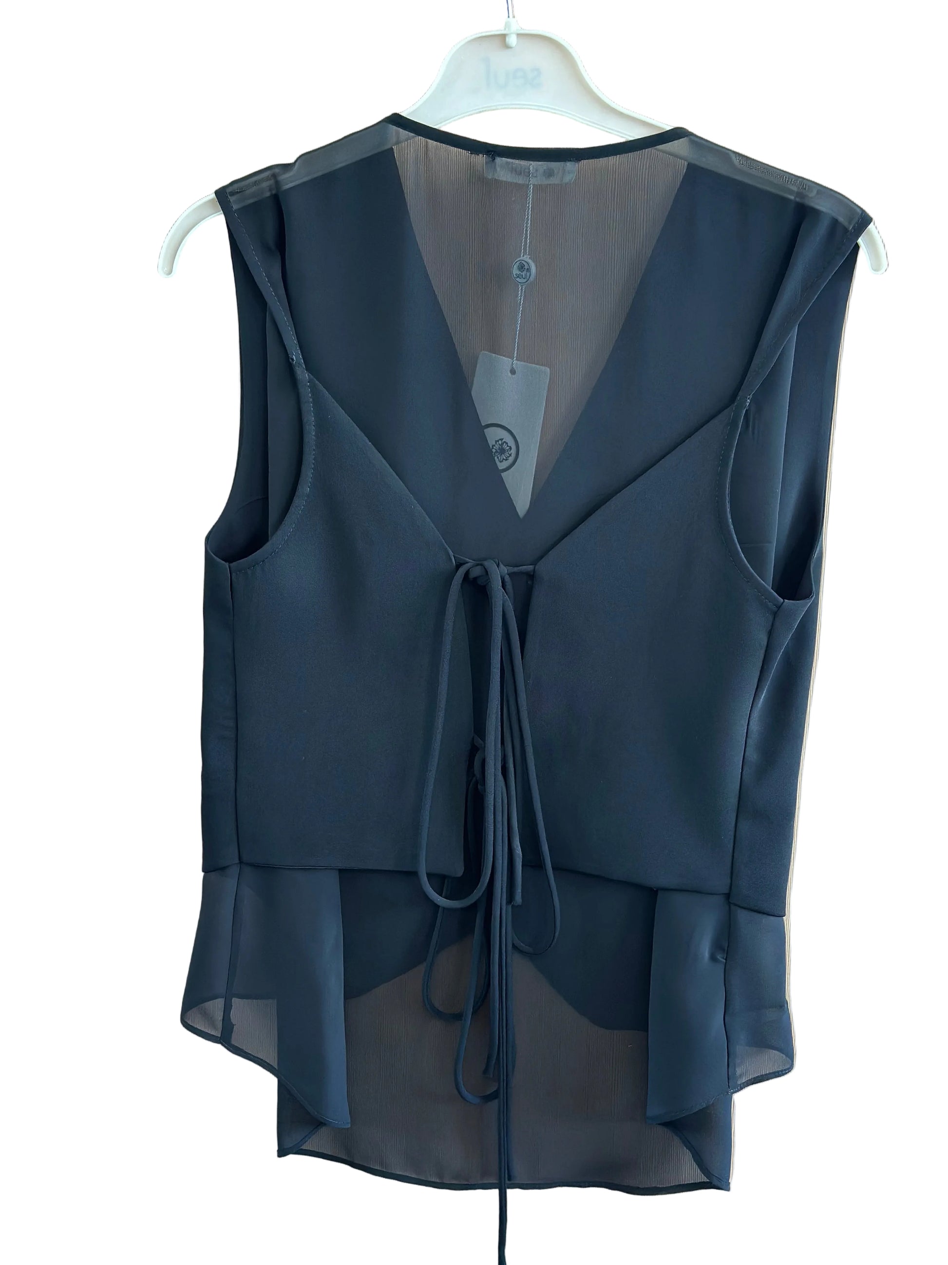 Black sheer top on a white hanger against a beige background