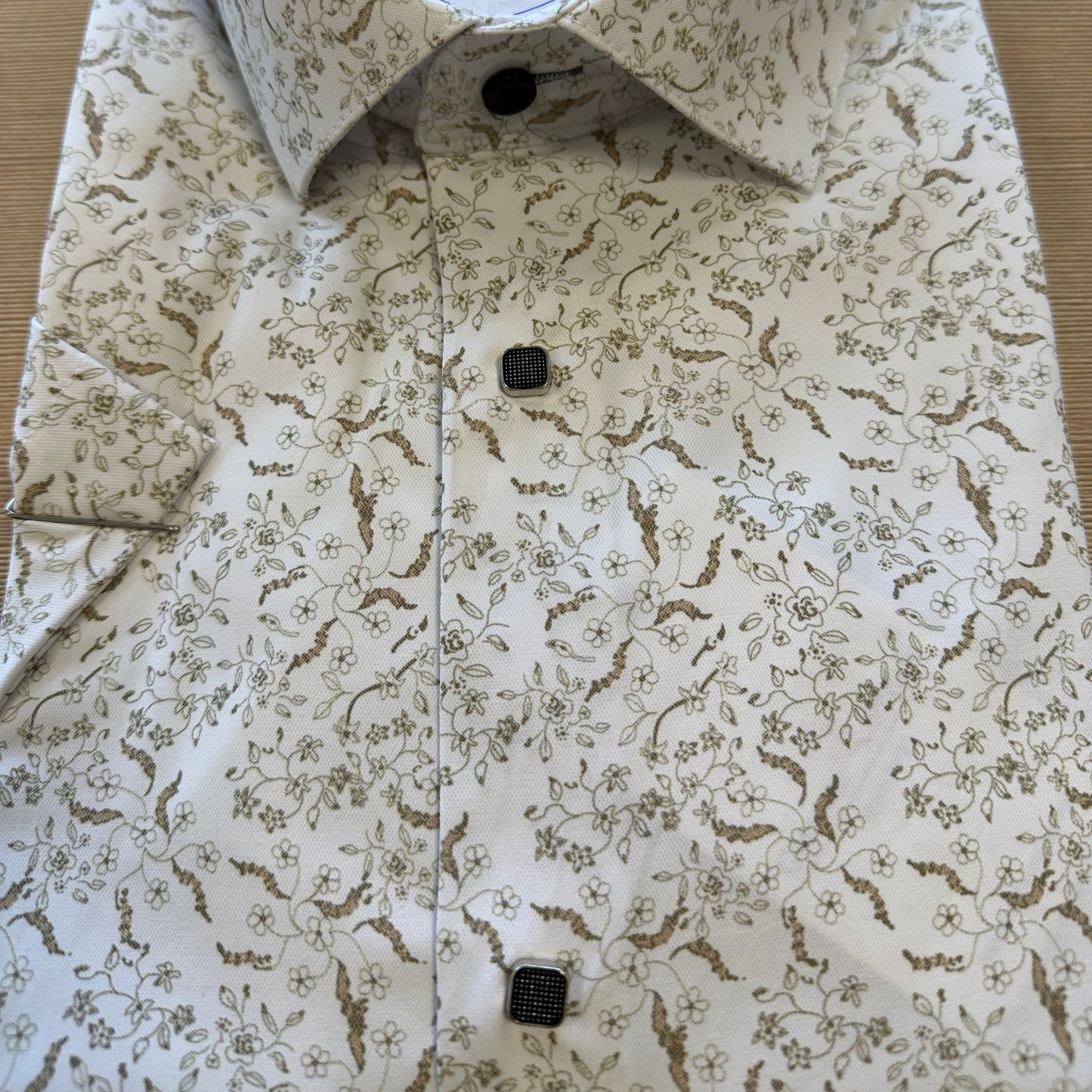 Sulankstyti trumpomis rankovėmis marškiniai su dekoratyviniu raštu ir sagomis.