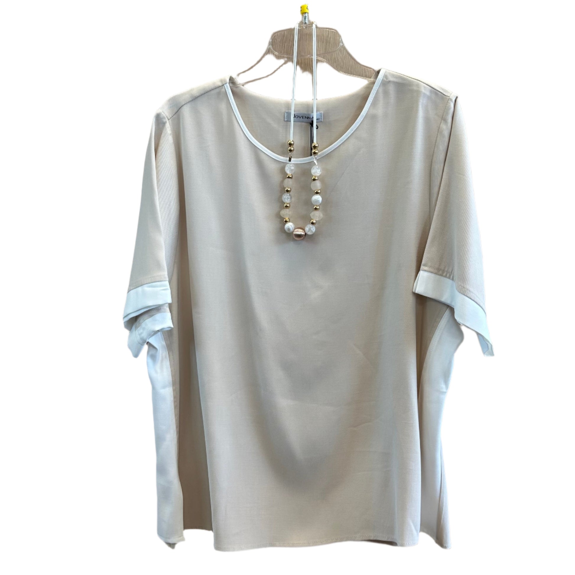 Elegantiška smėlio spalvos palaidinė su dekoratyviniu vėriniu, pakabinta ant pakabos.