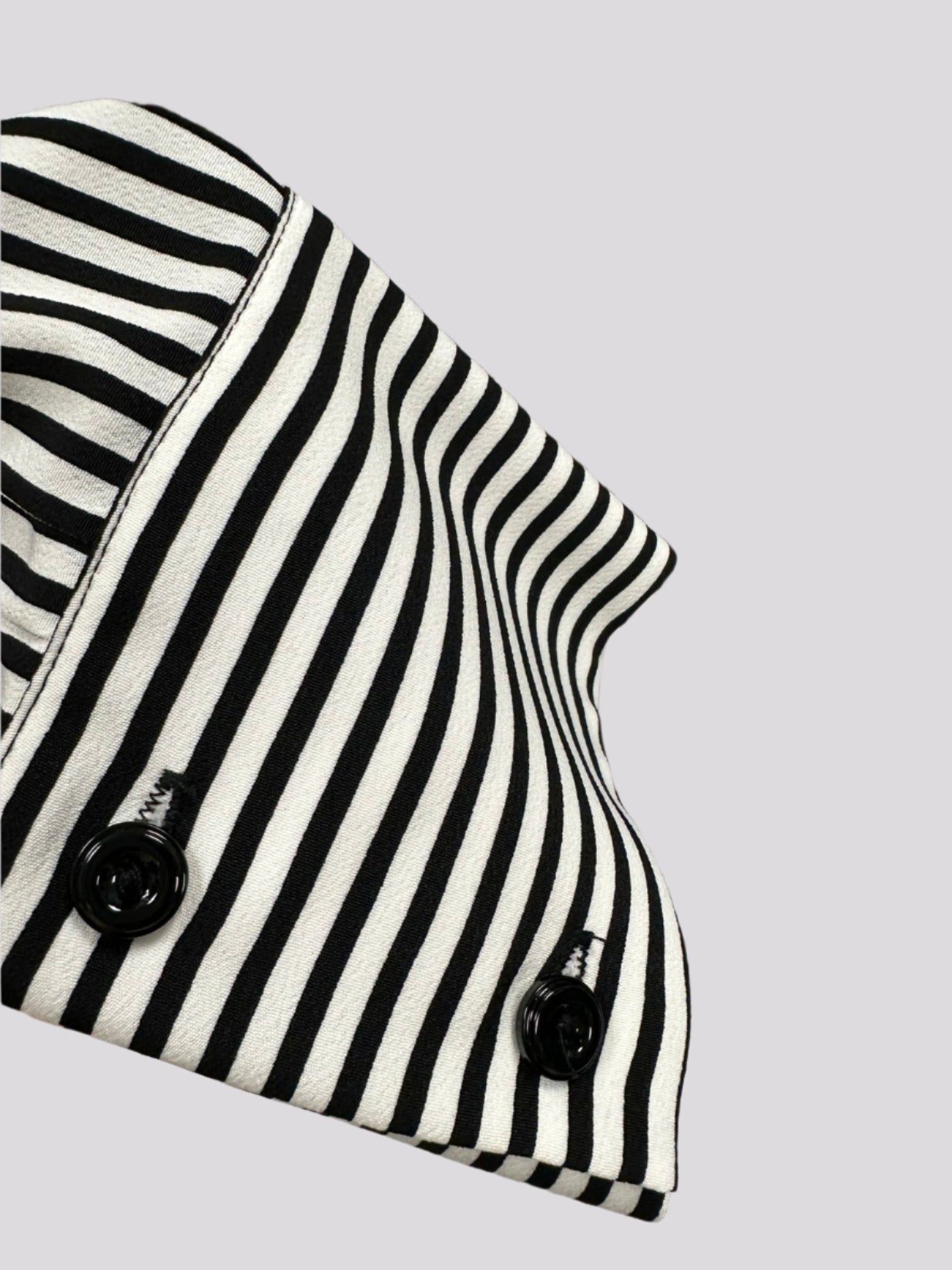 Dryžuoti moteriški marškiniai ant pakabos.