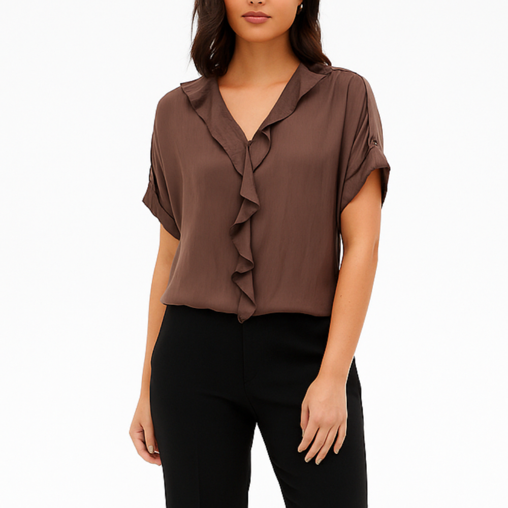 Woman wearing a brown blouse with ruffle details and black pants on a white background
