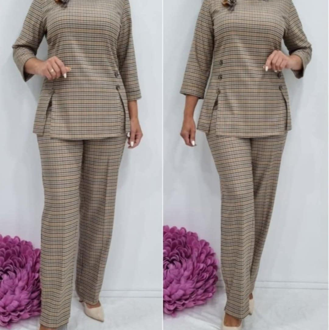 Languotas moteriškas kostiumėlis su dekoruotomis sagomis ir ilgomis kelnėmis.