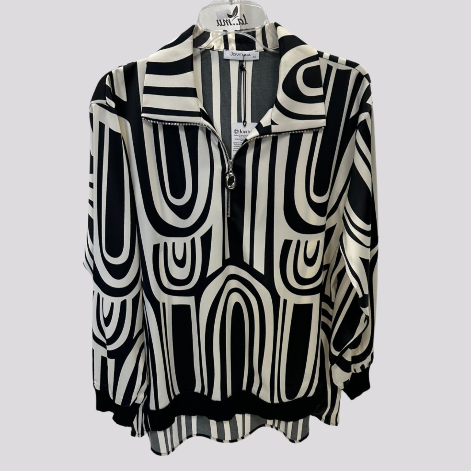 Stilinga kreminė palaidinė ant pakabos su kontrastingais akcentais, švelniai krentantis audinys.