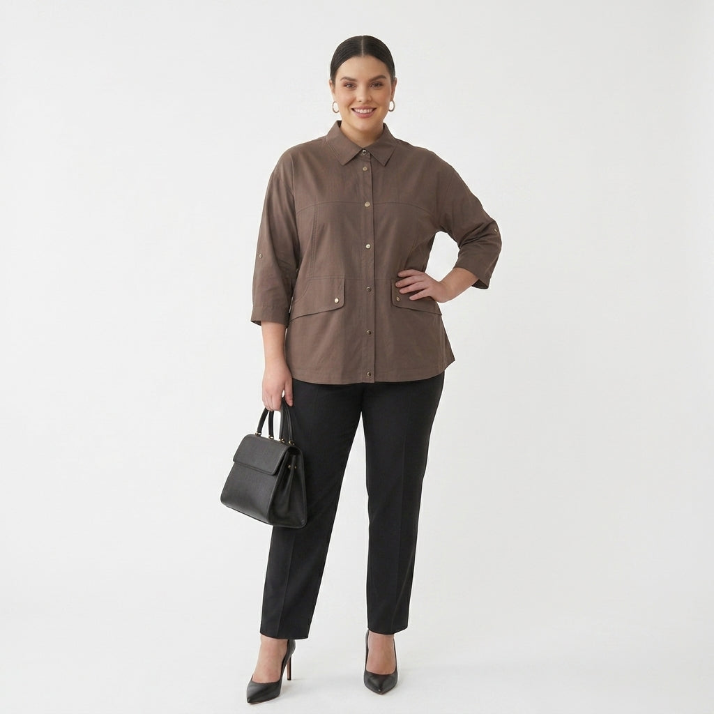 A woman modeling a brown button-up shirt with three-quarter sleeves, paired with black trousers, black heels, and a black handbag, against a plain white studio background.