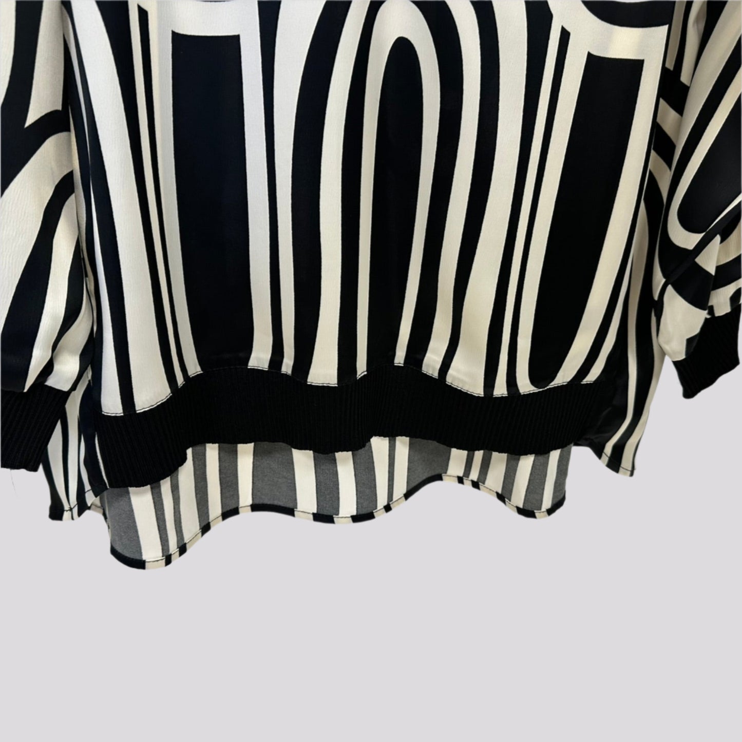 Stilinga kreminė palaidinė ant pakabos su kontrastingais akcentais, švelniai krentantis audinys.