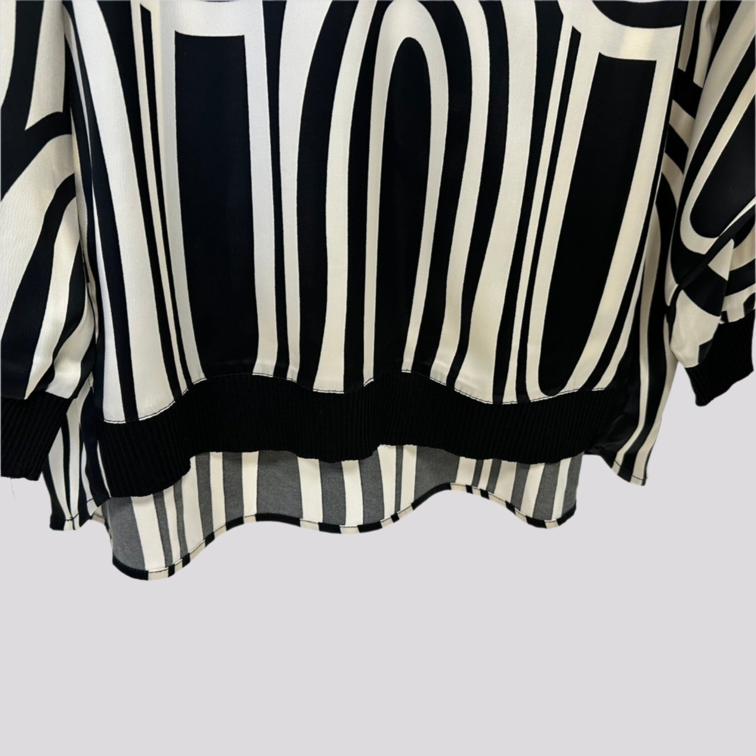 Stilinga kreminė palaidinė ant pakabos su kontrastingais akcentais, švelniai krentantis audinys.