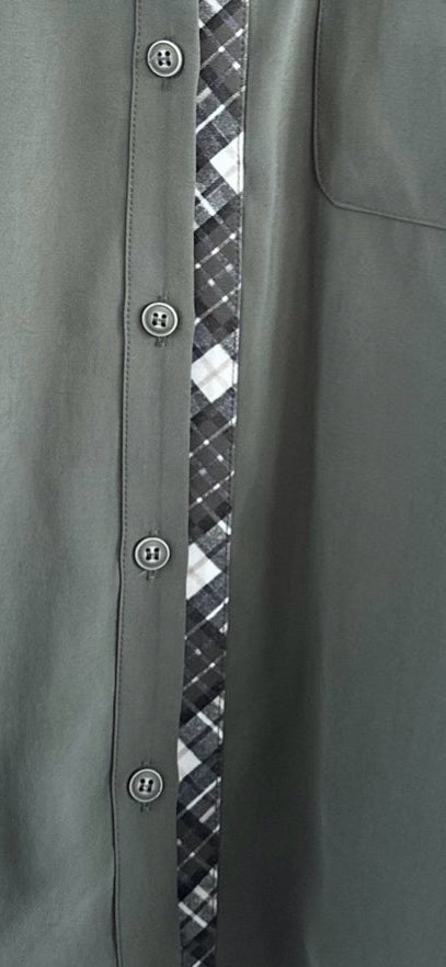 Close-up of a dark olive green button-up shirt featuring a vertical plaid stripe in black, white, and gray down the center, with matching buttons on the front.